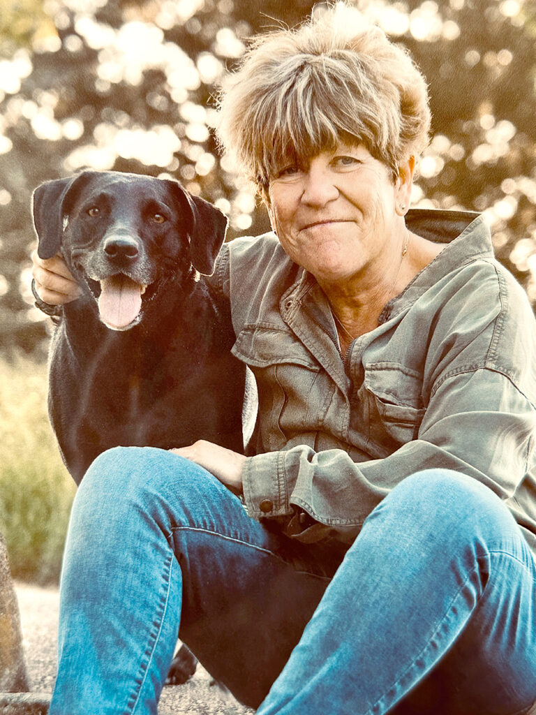 Portrait of abstract artist Janice Savage with her black Labrador outdoors, reflecting the natural inspiration behind her contemporary abstract paintings.