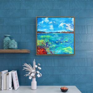 Framed abstract landscape painting, Overlook, displayed on a blue textured wall above a modern white console table with decorative vases, books and flowers.